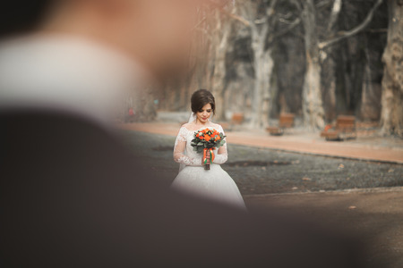 Beautiful couple of happy stylish newlyweds in the  park on their wedding day with bouquet.の写真素材