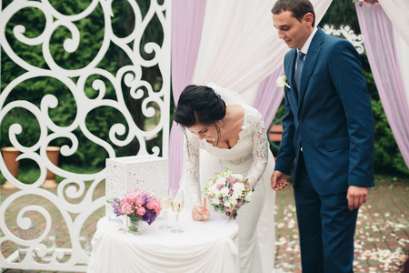Wedding couple standing under an arch of fresh flowers.の写真素材
