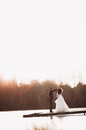 Elegant beautiful wedding couple posing near a lake at sunset.の写真素材