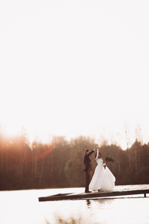 Elegant beautiful wedding couple posing near a lake at sunset.の写真素材