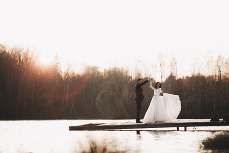 Elegant beautiful wedding couple posing near a lake at sunset.の写真素材