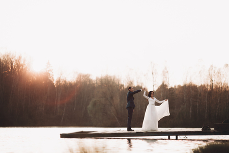 Elegant beautiful wedding couple posing near a lake at sunset.の写真素材