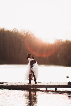 Elegant beautiful wedding couple posing near a lake at sunset.の写真素材