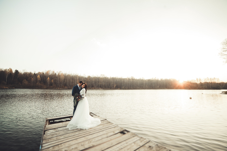 Elegant beautiful wedding couple posing near a lake at sunset.の写真素材