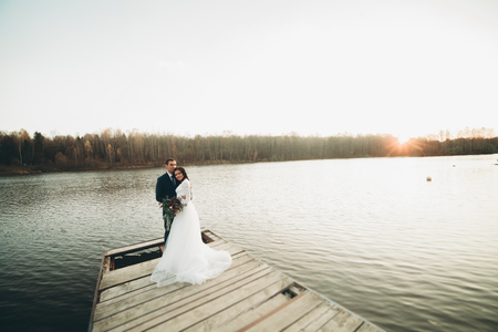 Elegant beautiful wedding couple posing near a lake at sunset.の写真素材
