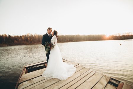 Elegant beautiful wedding couple posing near a lake at sunset.の写真素材