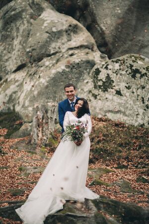 Gorgeous bride and groom kissing and hugging near the cliffs with stunning views.の写真素材