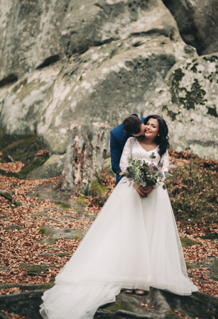 Gorgeous bride and groom kissing and hugging near the cliffs with stunning views.の写真素材