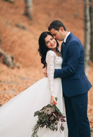 Gorgeous bride and groom kissing and hugging near the cliffs with stunning views.の写真素材