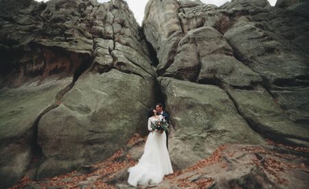 Gorgeous bride and groom kissing and hugging near the cliffs with stunning views.の写真素材