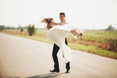 Beautiful wedding couple, bride and groom posing on road.の写真素材