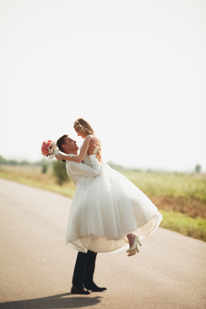 Beautiful wedding couple, bride and groom posing on road.の写真素材