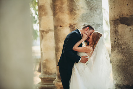 Beautiful romantic wedding couple of newlyweds kissing near old castle.の写真素材