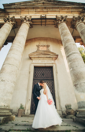 Beautiful romantic wedding couple of newlyweds kissing near old castle.の写真素材