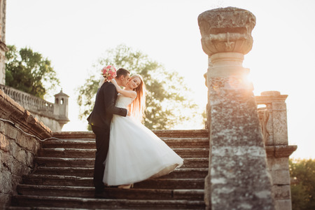Beautiful romantic wedding couple of newlyweds hugging near old castle.の写真素材