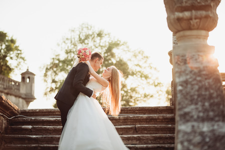 Beautiful romantic wedding couple of newlyweds hugging near old castle.の写真素材