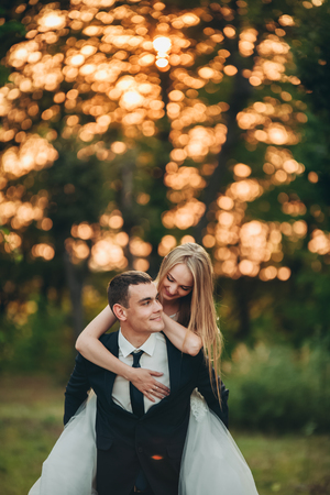 Beautiful romantic wedding couple of newlyweds in park on sunset.の写真素材