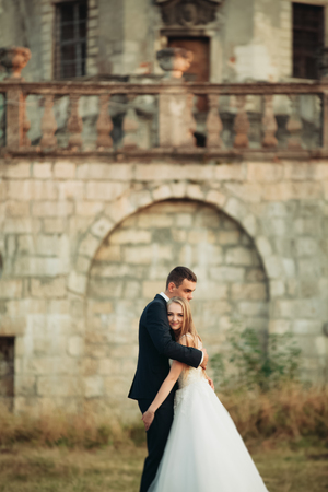 Beautiful romantic wedding couple of newlyweds hugging near old castle.の写真素材