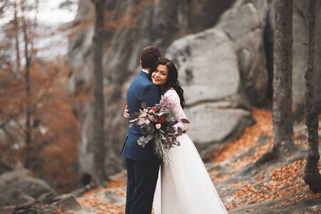 Gorgeous wedding couple hugging in forest with big rocks.の写真素材