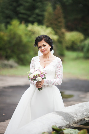 Beautiful brunette bride in elegant white dress holding bouquetの写真素材