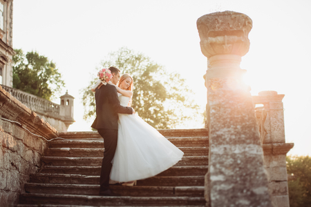 Beautiful romantic wedding couple of newlyweds hugging near old castle.の写真素材