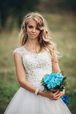 Luxuty portrait of blonde bride with bridal bouquet in autumn.の写真素材