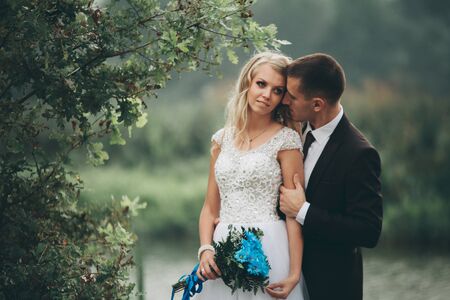 Romantic wedding couple, man and wife, posing near beautiful lake.の写真素材