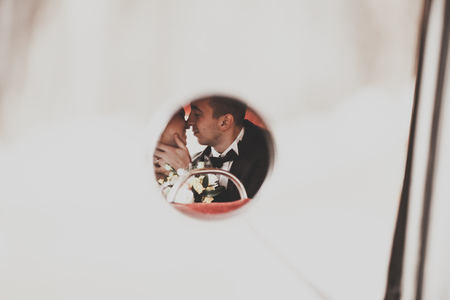Stylish wedding couple, bride and groom kissing and hugging in retro car in autumn.の写真素材