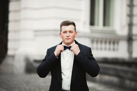 man groom posing in old city.