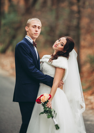 Happy wedding couple, bride and groom posing in park autumn.の写真素材