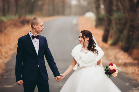 Happy wedding couple, bride and groom posing in park autumn.の写真素材