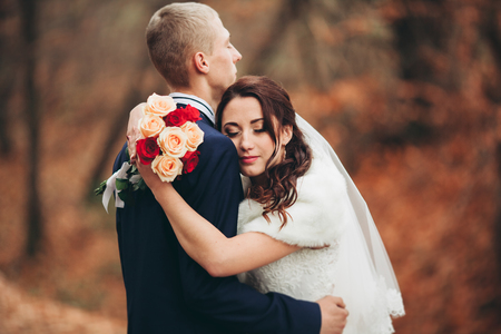 Happy wedding couple, bride and groom posing in park autumn.の写真素材