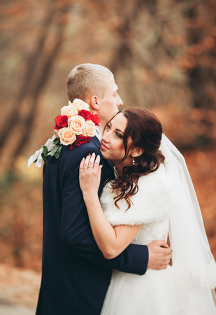 Happy wedding couple, bride and groom posing in park autumn.の写真素材