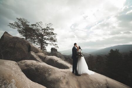 Gorgeous bride and groom kissing and hugging near the cliffs with stunning views.の写真素材
