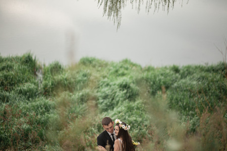 Elegant beautiful wedding couple posing near lake in park.の写真素材