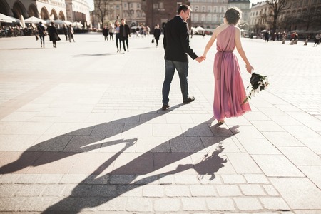 beautiful couple, bride with pink dress walking in the old city Krakow, their shadows.の写真素材