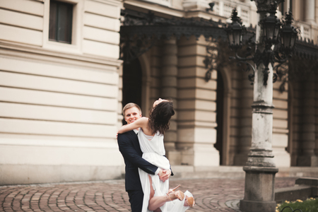 Beautiful wedding couple, bride, groom hugging against the background of theater.の写真素材