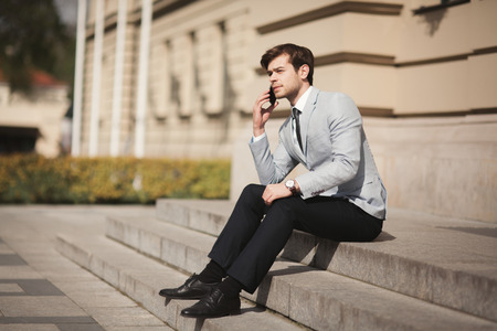 Stylish young businessman talking on the phone outdoors.の写真素材