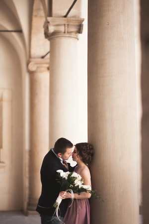 Happy wedding couple, groom, bride with pink dress hugging and kissing each other on the background walls in castle.の写真素材