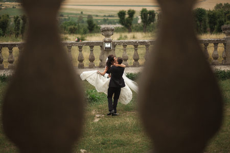 Beautiful romantic wedding couple of newlyweds hugging and kissing near old castle.の写真素材