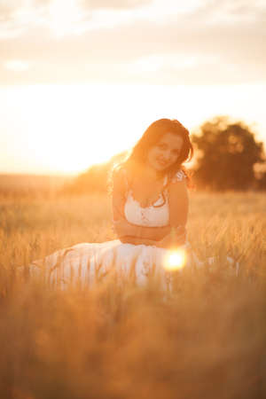 Happy beautiful young bride outside on a summer meadow at the sunset.の写真素材
