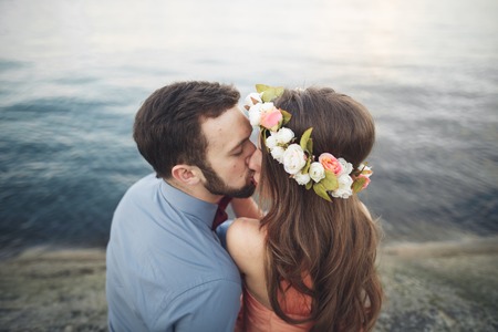 Wedding couple sitting on large stone around blue sea.の写真素材