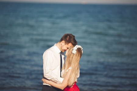 Young happy couple walking on beach smiling holding around each other. Love story.の写真素材
