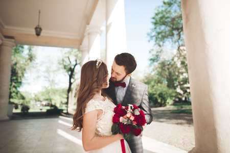 Beautiful couple, bride and groom posing near big white column.の写真素材