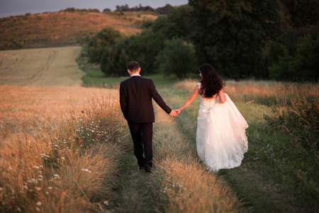 Beautiful romantic wedding couple of newlyweds hugging in park on sunset.の写真素材