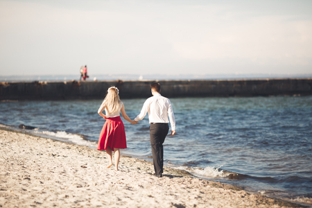 Young happy couple walking on beach smiling holding around each other. Love story.の写真素材