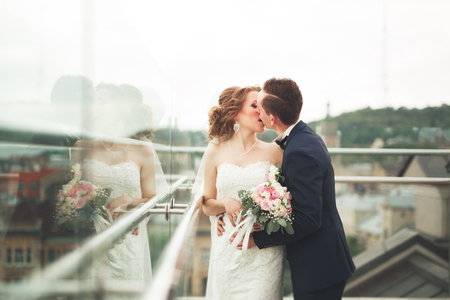 Happy wedding couple, bride, groom kissing with view of old city.の写真素材