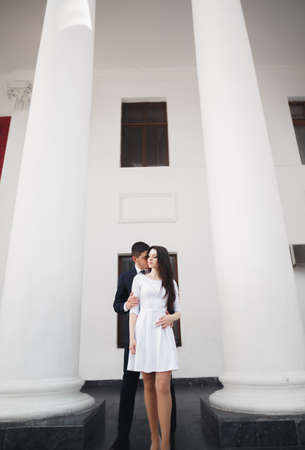 Beautiful couple, bride and groom posing near big white column.の写真素材