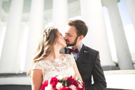 Beautiful couple, bride and groom posing near big white column.の写真素材