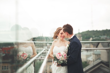 Happy wedding couple, bride, groom kissing with view of old city.の写真素材